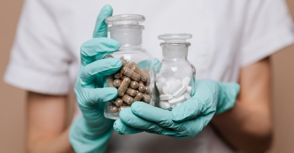 Close-up of a healthcare professional holding glass bottles with capsules and tablets, wearing gloves.
